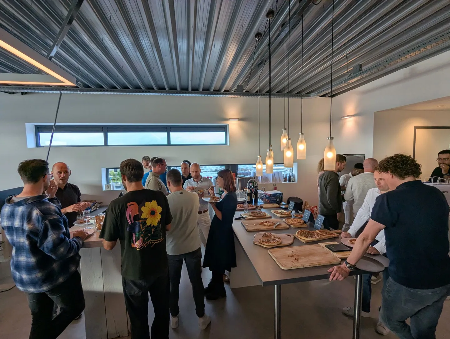Attendees gathered around long tables with pizza at the Cream office