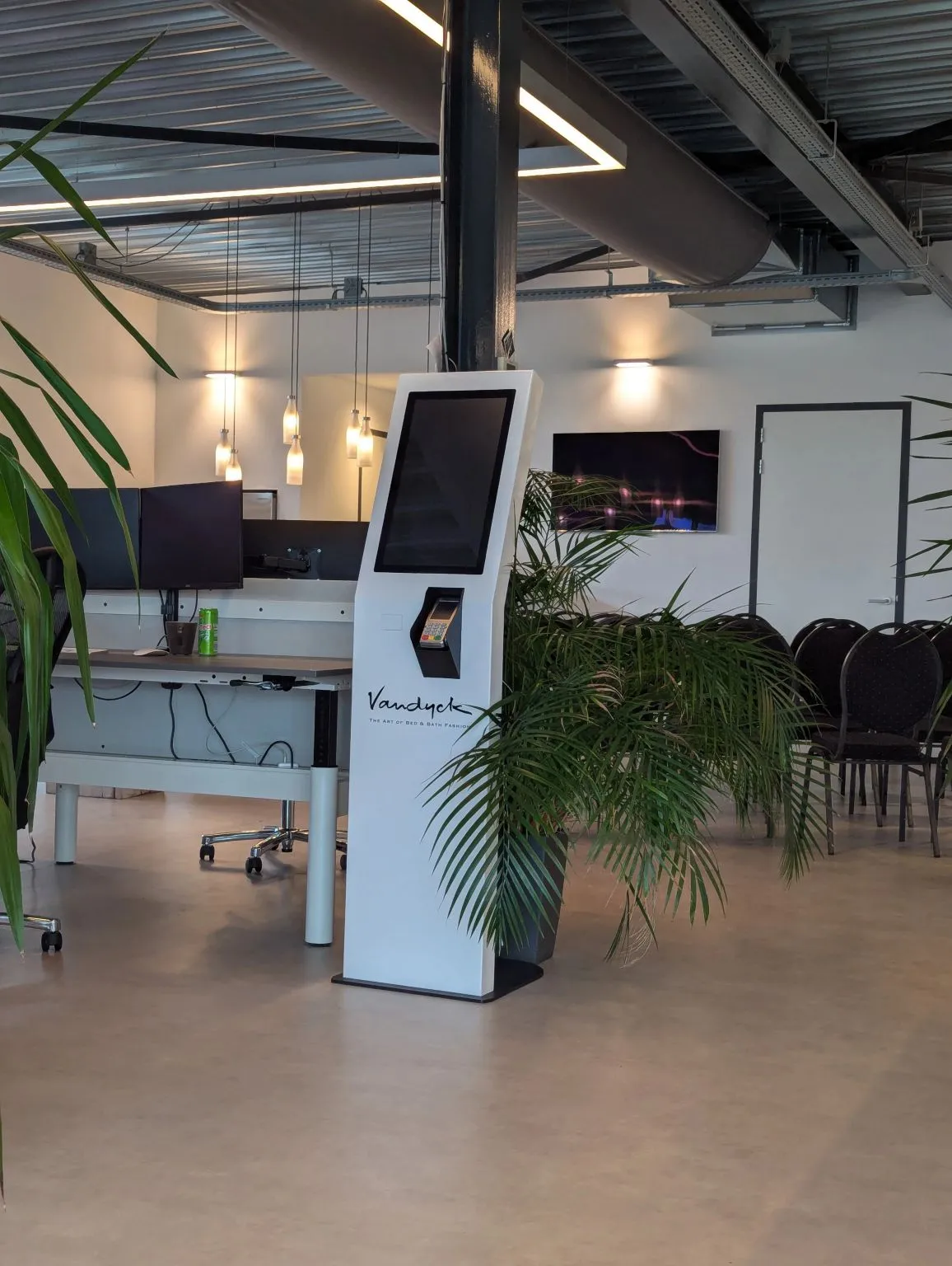 The dimly lit meetup room with a kiosk and plants before the talks